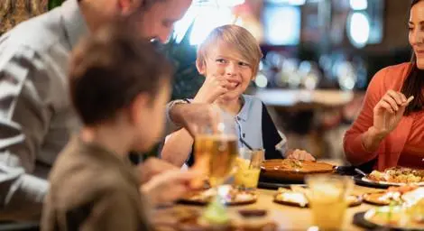 two-young-boys-eating-food-at-table-with-older-man-and-older-woman