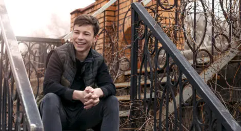 smiling-teenage-boy-sitting-on-metal-outdoor-staircase