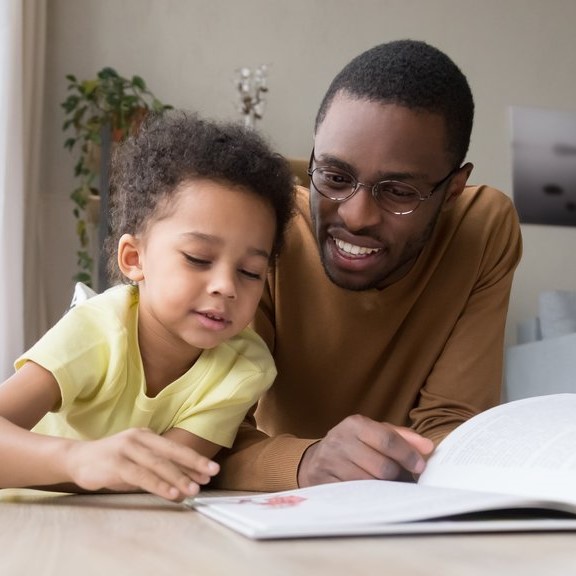Adopter father reading on the floor with his adopted child