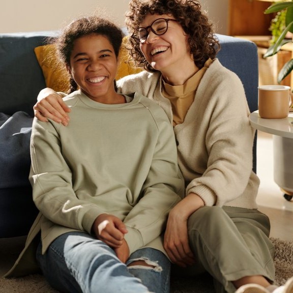 Foster mother hugging foster child while sitting on the floor