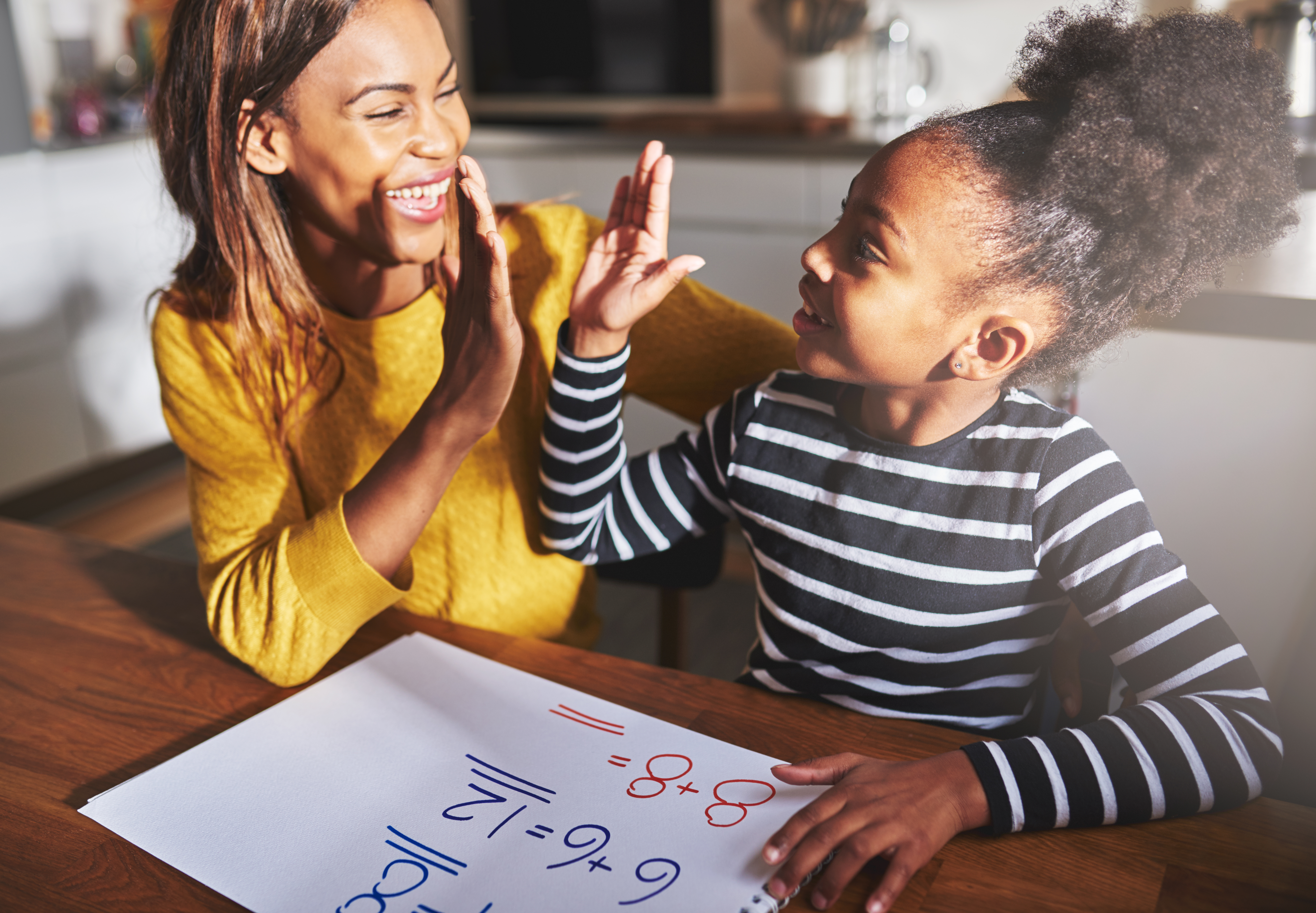 woman-high-fiving-little-girl-while-seated-at-a-table