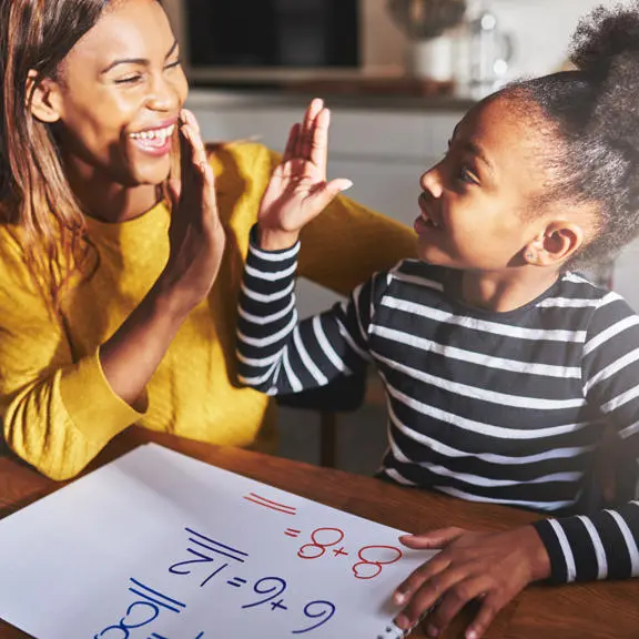 woman-high-fiving-little-girl-while-seated-at-a-table