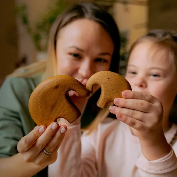 lady-and-girl-side-by-side-holding-up-wooden-elephant-ornaments
