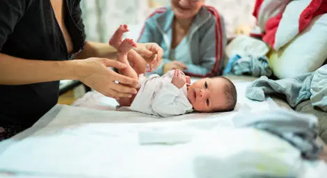 baby-laying-on-changing-mat-with-lady-standing-over