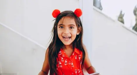 smiling-girl-wearing-red-pompon-headband-holding-tablet