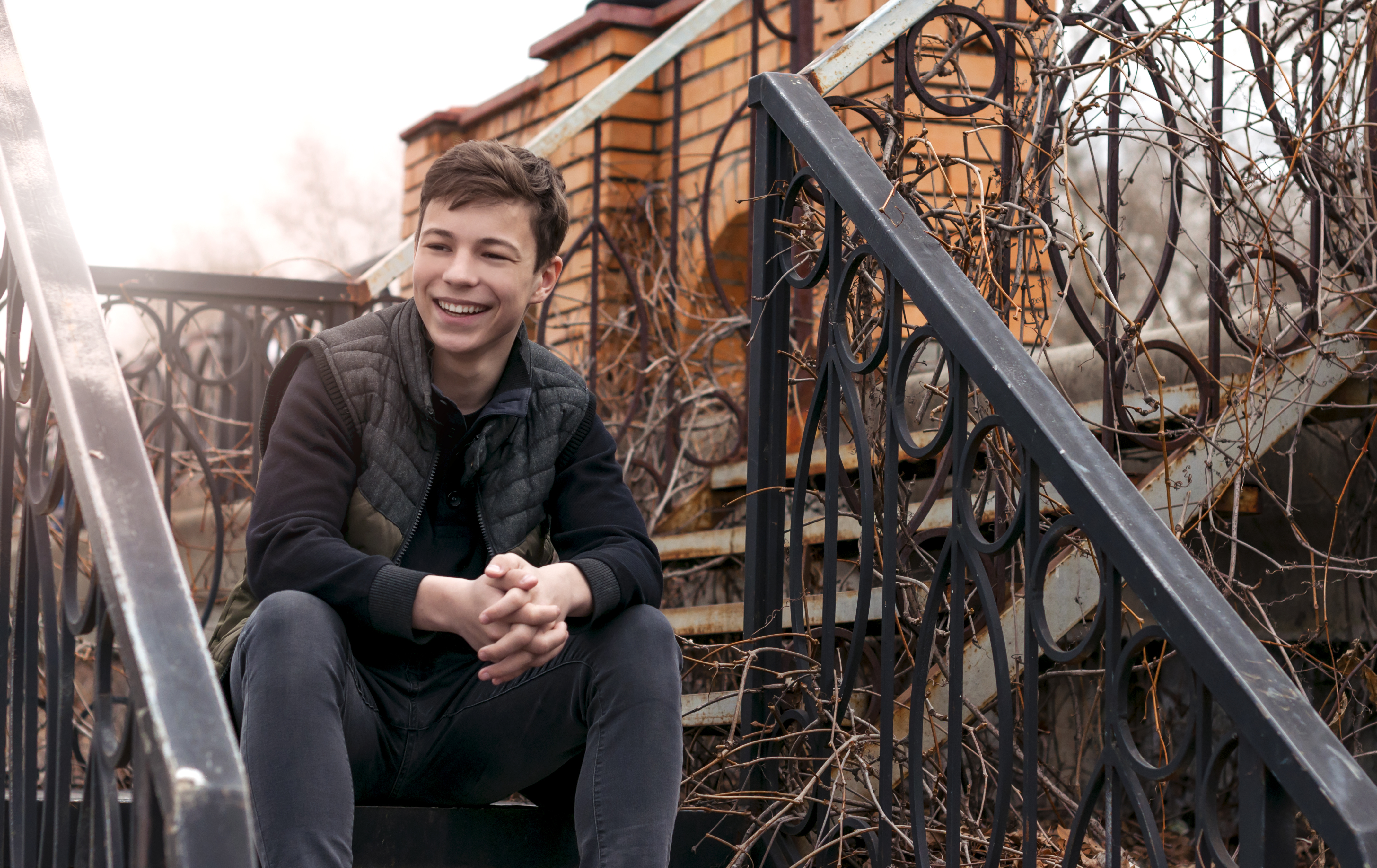 smiling-teenage-boy-sitting-on-metal-outdoor-staircase